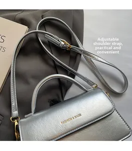 Detail of silver textured leather flap bag with adjustable strap and top handle