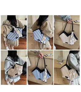 Striped canvas tote bag with black leather trim and decorative ribbon in home setting