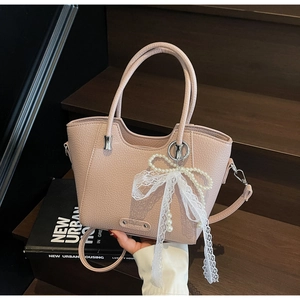 Détail du sac cabas rose en cuir texturé avec nœud en dentelle et bijou en perles