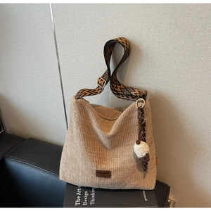 Detail of hand-woven straw tote bag with geometric strap and white tassel charm