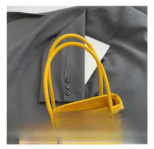 Detail showing yellow PU leather texture, dual handles and silver metal accents of the bag