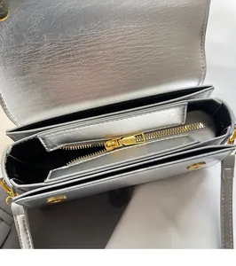 Detail view of silver textured leather bag featuring golden hardware and three compartments