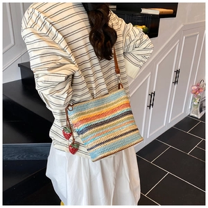 Detail of colorful woven straw bucket bag with strawberry charms and leather strap