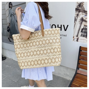 Detail of woven straw shoulder bag with geometric patterns and brown leather straps