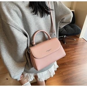 Detail of pink lychee leather shoulder bag with FASHION&BAGS printed text and fine strap