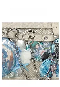 Detail der klaren ITA-Tasche mit blauen Buttons und silberner herzförmiger Metallkette