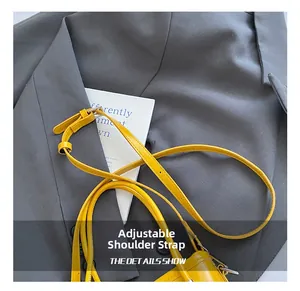 Detail of adjustable bright yellow leather shoulder strap with metallic buckle on bag
