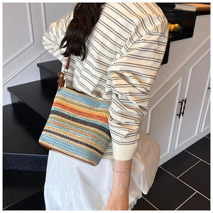 Detail of multi-color woven straw bucket bag with adjustable brown leather shoulder strap