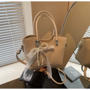 Détail du sac cabas en cuir grainé beige avec nœud en perles et ruban en dentelle