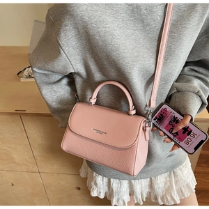Detail of pink lychee leather handbag featuring silver lettering and top handle design