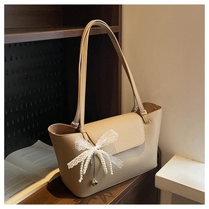 Detailed texture of beige pebbled leather tote with lace bow and pearl pendant