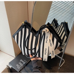 Detail of striped canvas tote bag showing black and white patterns with leather trim