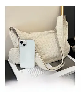 Detail of cream-white pleated crossbody bag with matching mini pouch and phone comparison