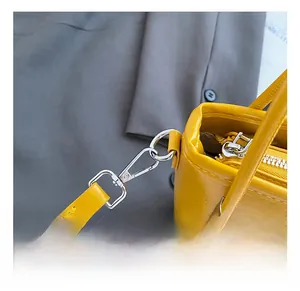 Close-up of bright yellow shoulder bag featuring silver metal hook and zipper detail