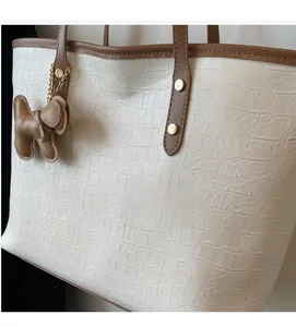 Detail of croco-patterned tote bag with brown leather straps and cute dog charm pendant