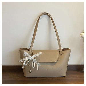 Detail of beige tote bag showing lychee grain texture with lace bow and pearl charm