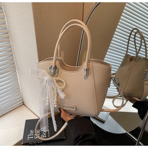 Vue détaillée du sac cabas beige avec texture litchi et décoration nœud perlé