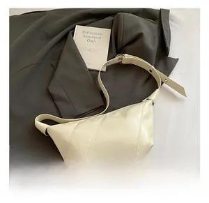 Détail du sac demi-lune en cuir crème avec coutures verticales et boucle argentée