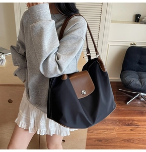 Detail of large nylon tote bag with brown leather flap and silver metal buckle