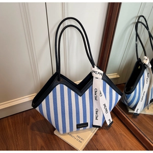Detail of blue striped canvas tote with V-cut opening and fashion label on wooden floor