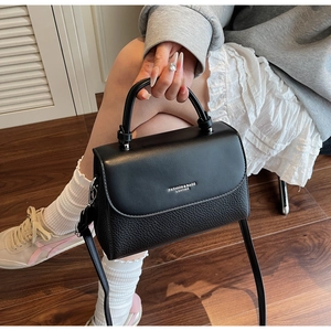 Close-up of black pebbled leather handbag with silver lettering and rounded handle