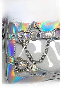 Détail du sac holographique avec boucle en métal en forme de cœur et chaînes argentées