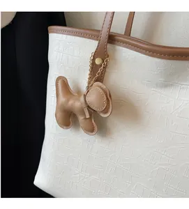 Close-up of crocodile texture tote bag featuring a cute brown puppy leather bag charm