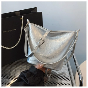 Makro-Detail der silbernen Metallic-Beuteltasche mit Faltenstruktur und Trageriemen