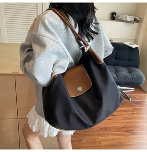 Classic black nylon tote bag with brown leather handles worn by a model in a room