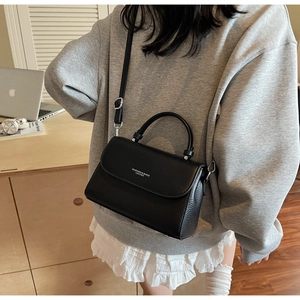 Detail of black leather crossbody bag with adjustable strap and embossed fashion logo