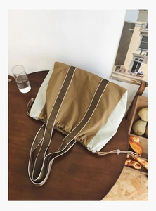 Close-up of large canvas tote bag with drawstring closure in brown and beige colors
