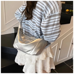 Sac hobo métallisé argenté porté à l'épaule par un mannequin de dos en intérieur