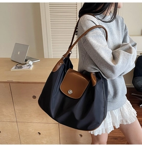 Close-up of a black nylon tote bag with brown leather accents and metal clasp lock