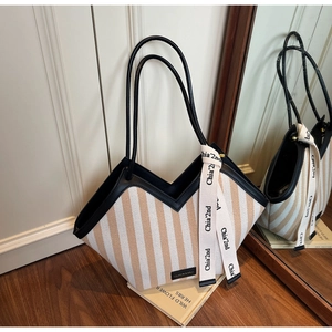 Detail of striped canvas tote bag showing the side ribbon decor and V-shaped top cut