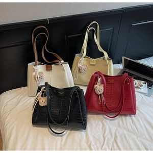 Detailed view of four crocodile-embossed tote bags in white, beige, black, and red colors
