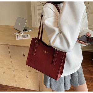 Detailed shot of dark red leather tote bag with gold lettering in a lifestyle setting