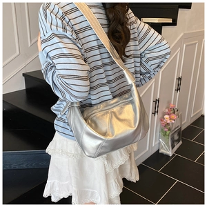 Gros plan sur le sac croissant argenté métallisé avec large bandoulière sur un mannequin