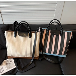 Detailed view of striped canvas tote bags with leather trim and detachable shoulder straps