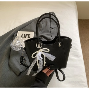 Détail du sac cabas en cuir grainé noir avec nœud en dentelle et perles argentées