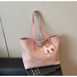 Detail of pink crocodile embossed tote bag with cute dog pendant and slim shoulder strap