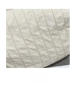 Detail of white quilted handbag featuring diagonal pleated fabric and silver zipper