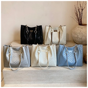 Détail de la texture lettre embossée et des bandoulières en chaîne sur les sacs cabas
