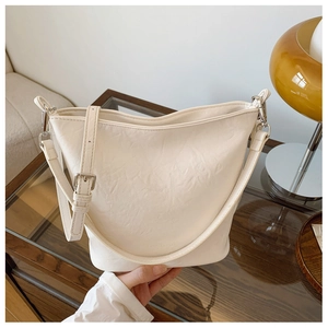 Detail der cremeweißen Eimertasche aus Kunstleder mit Lychee-Narben und Silberschnalle