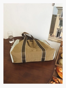 Detailed close-up of a large khaki tote bag with drawstring on a wooden table