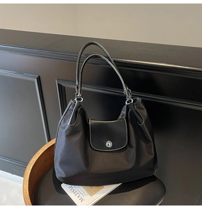 Detail of black nylon tote bag featuring white contrast stitching and silver hardware buckle