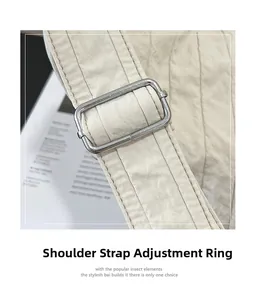 Close-up of the adjustable silver metal buckle on the off-white nylon shoulder bag strap