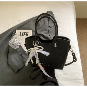 Détail du sac cabas noir grainé avec accessoire nœud perlé et ruban en dentelle