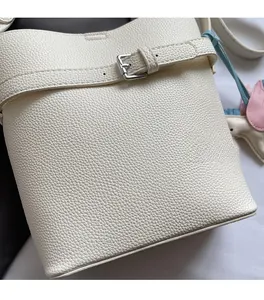 Close-up of white lychee pattern leather bucket bag with silver buckle and pony charm