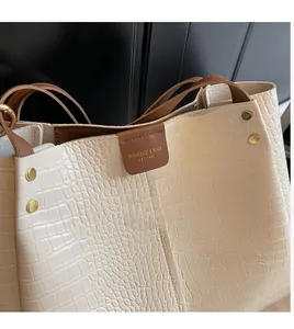 Detail of crocodile embossed faux leather tote with magnetic closure and brand logo