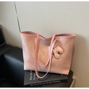 Close-up of pink tote bag with crocodile texture and leather puppy charm detail